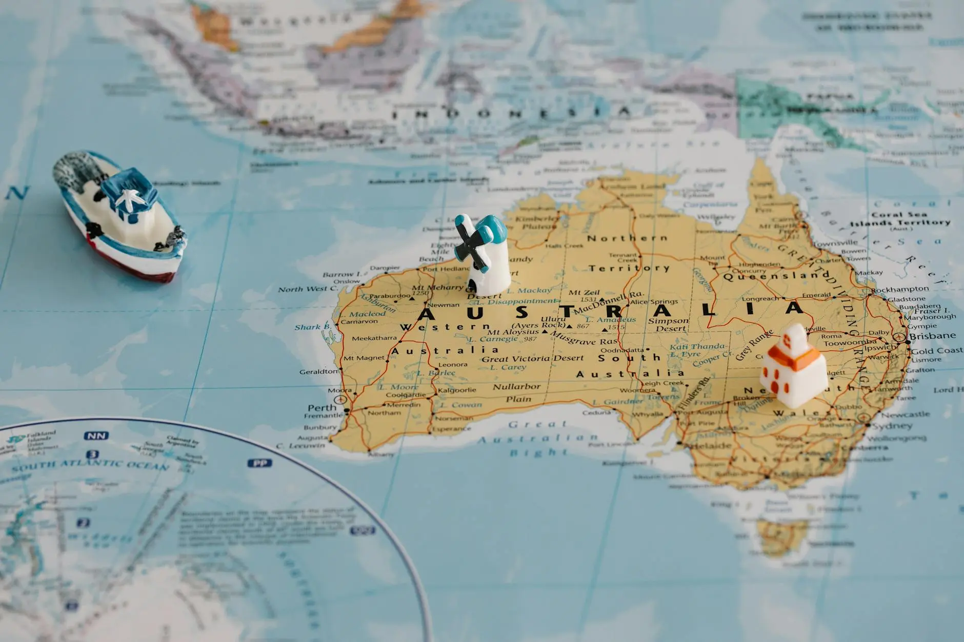 A map of Australia with a small boat and house figurines placed on it.