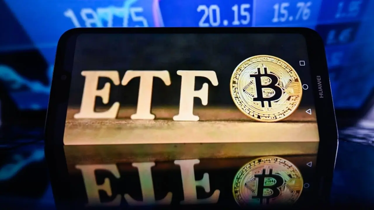 Smartphone displaying the letters 'ETF' next to a Bitcoin symbol on a reflective surface.