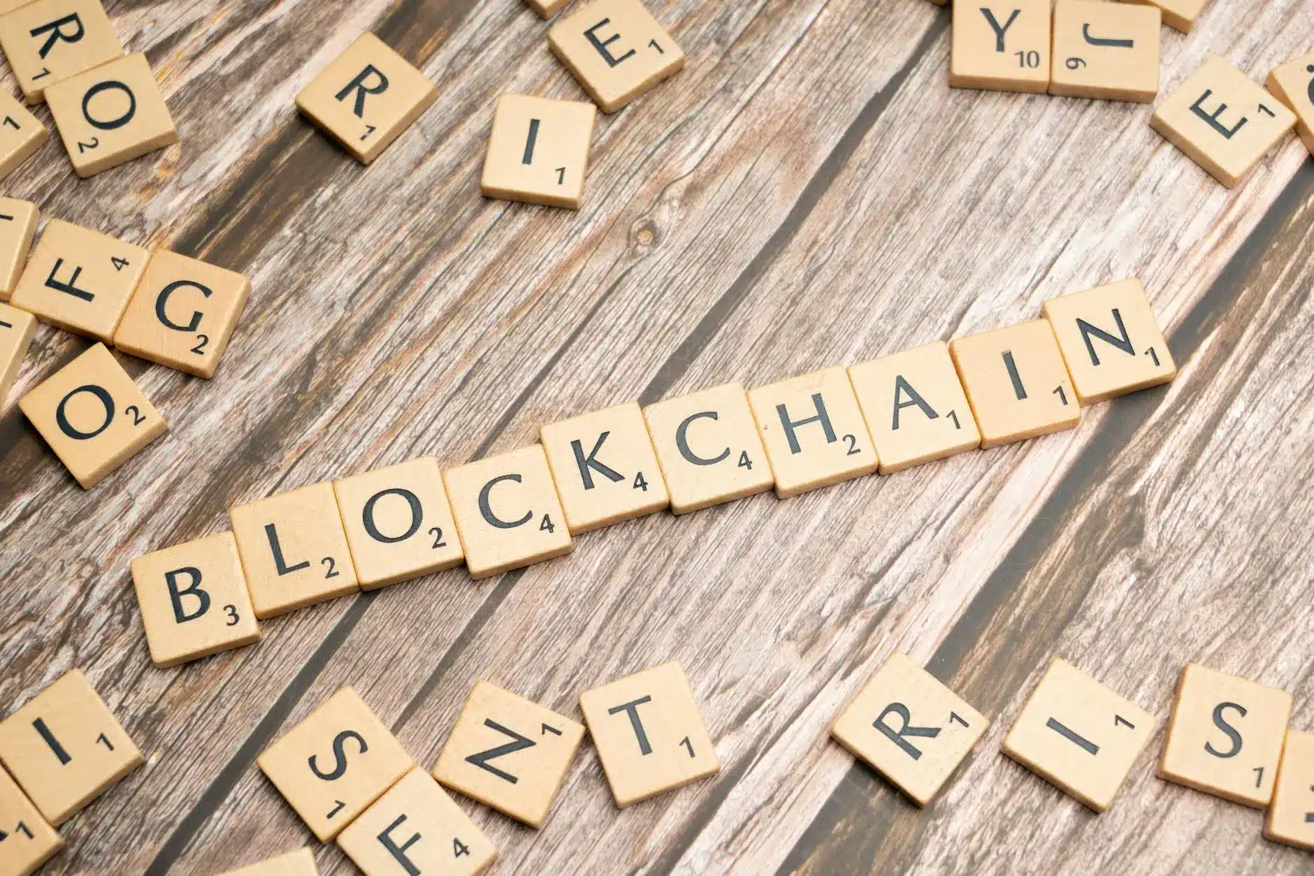 Scrabble tiles spelling 'BLOCKCHAIN' on a wooden background.