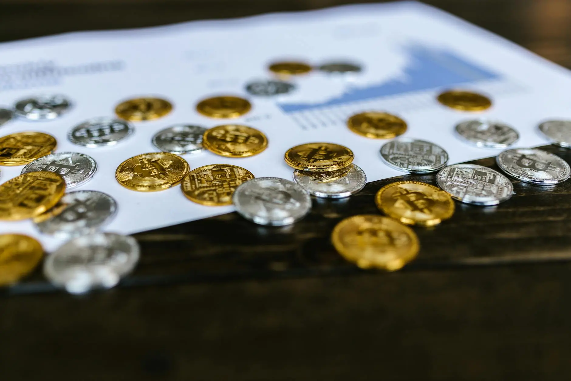 Gold and silver coins scattered on a table next to a financial report.