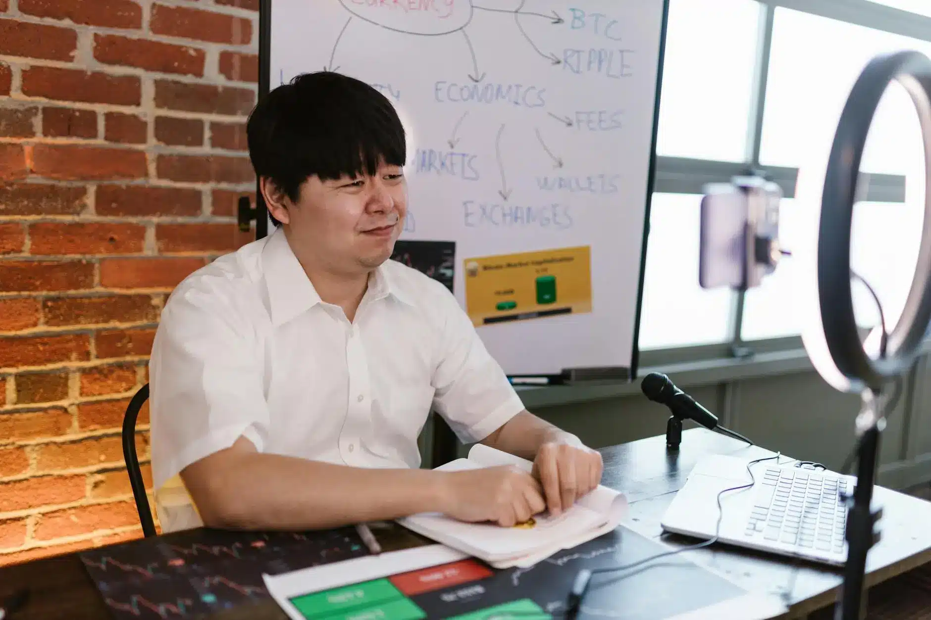 Person discussing cryptocurrency with notes and charts in front of a whiteboard.