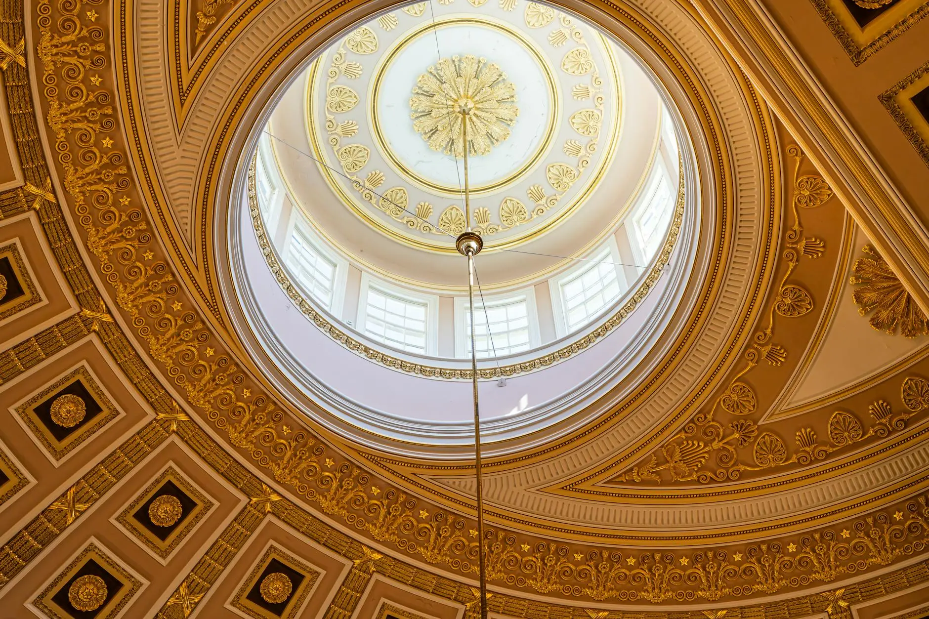 Intricate dome ceiling with gold details and a skylight in a historic building.