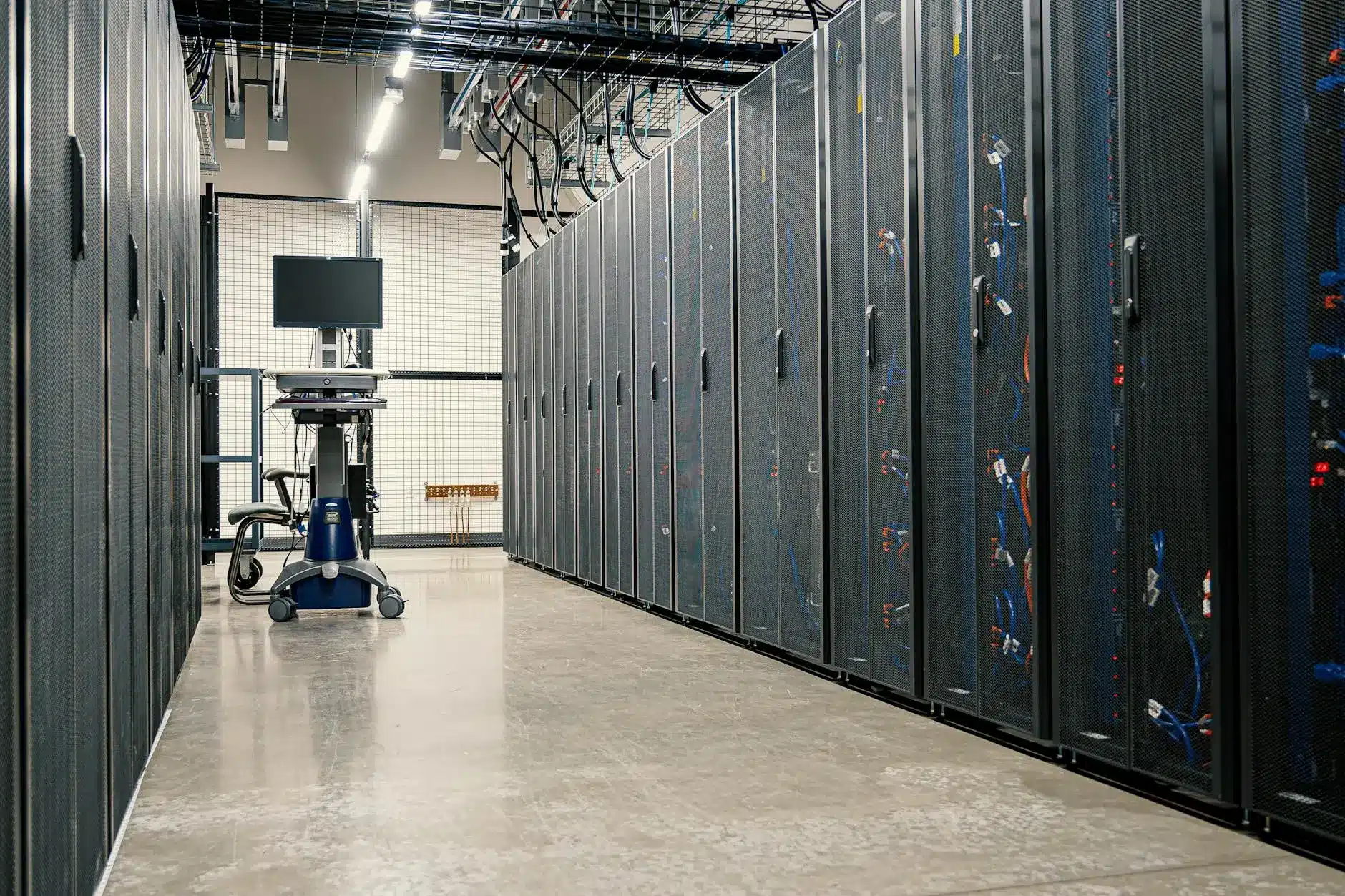 A row of data center servers with cables and a workstation on wheels.