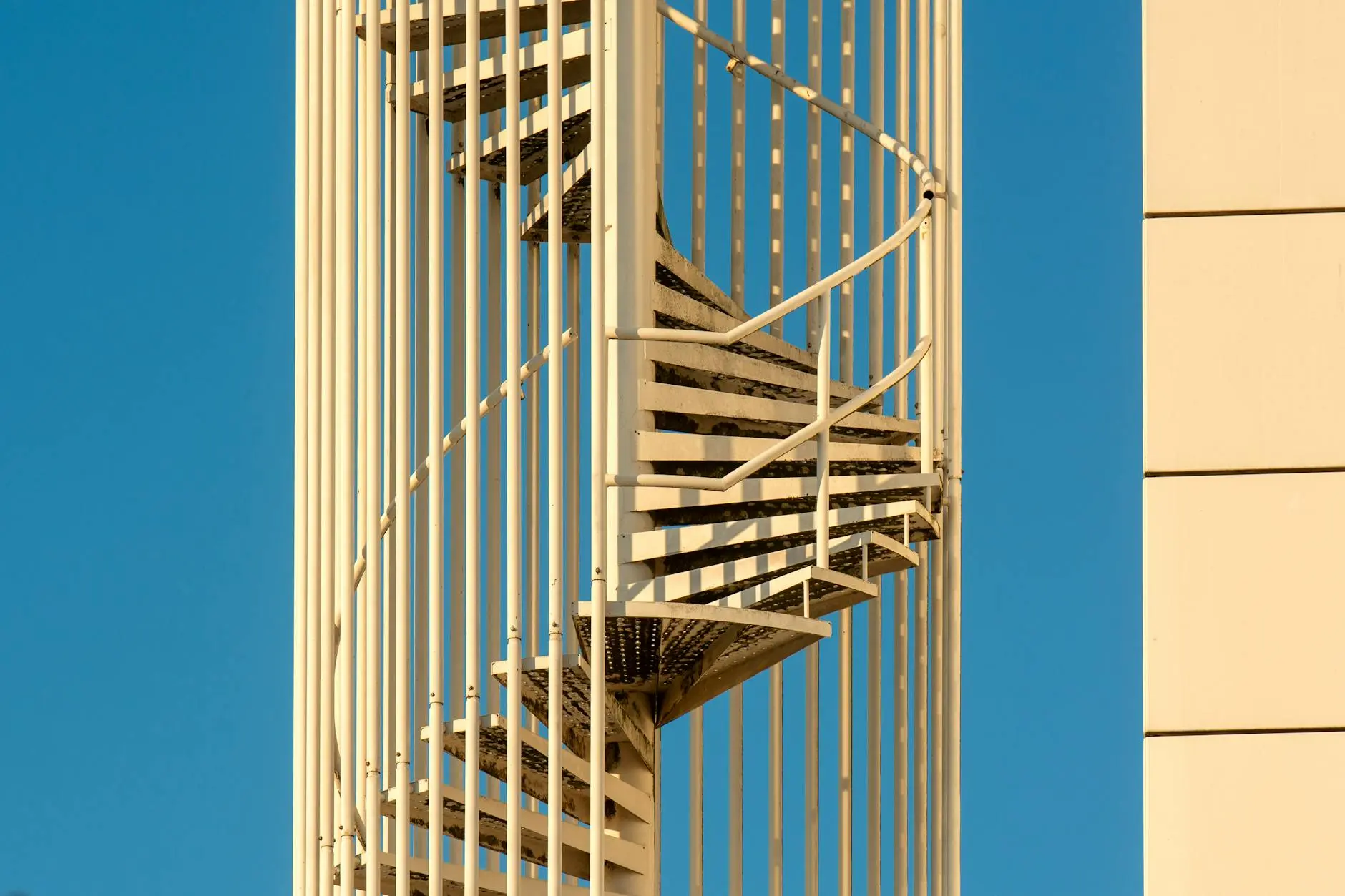 Close-up view of a spiral staircase structure against a clear blue sky.