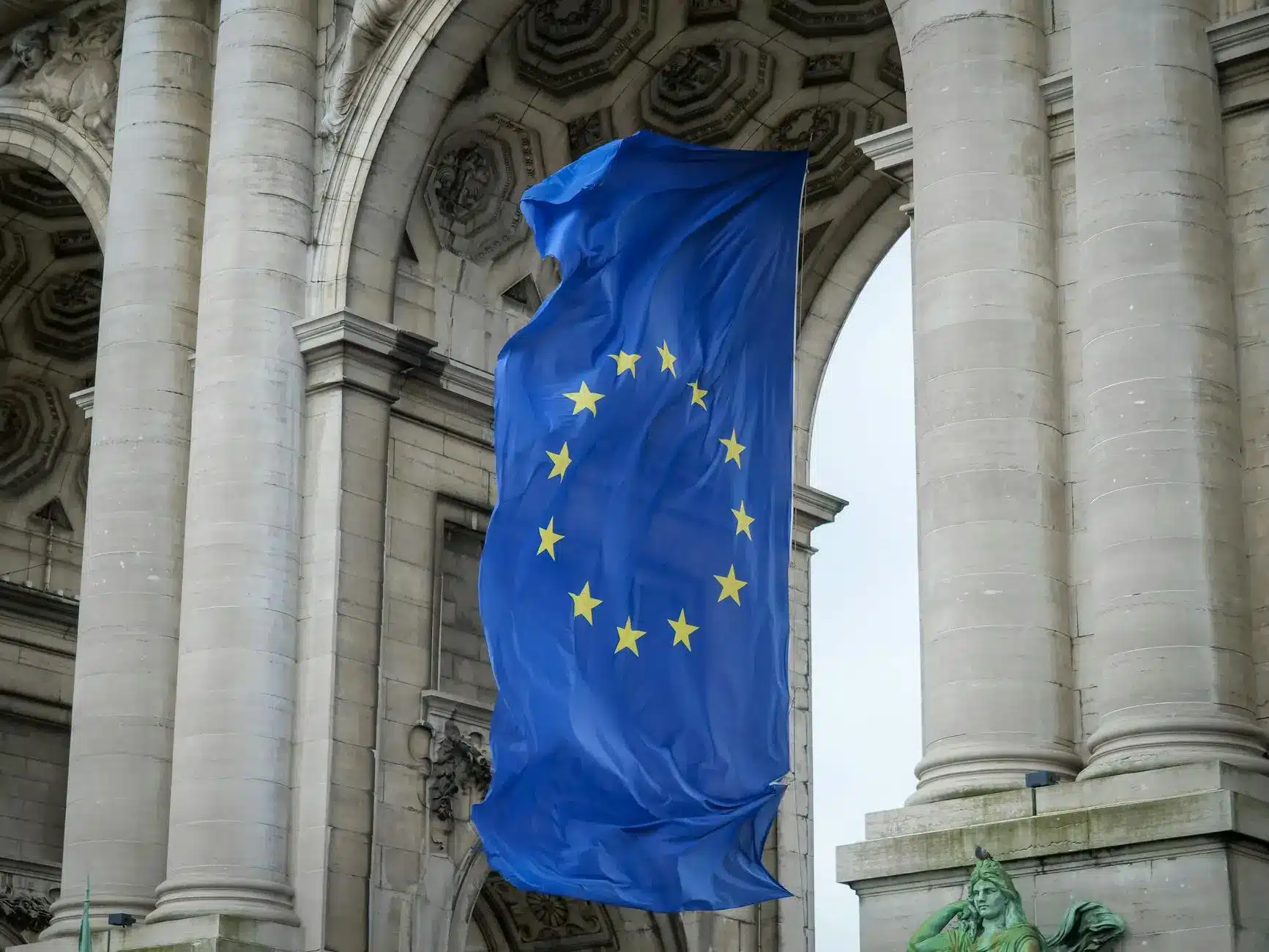 European Union flag waving in front of a historic building with columns.