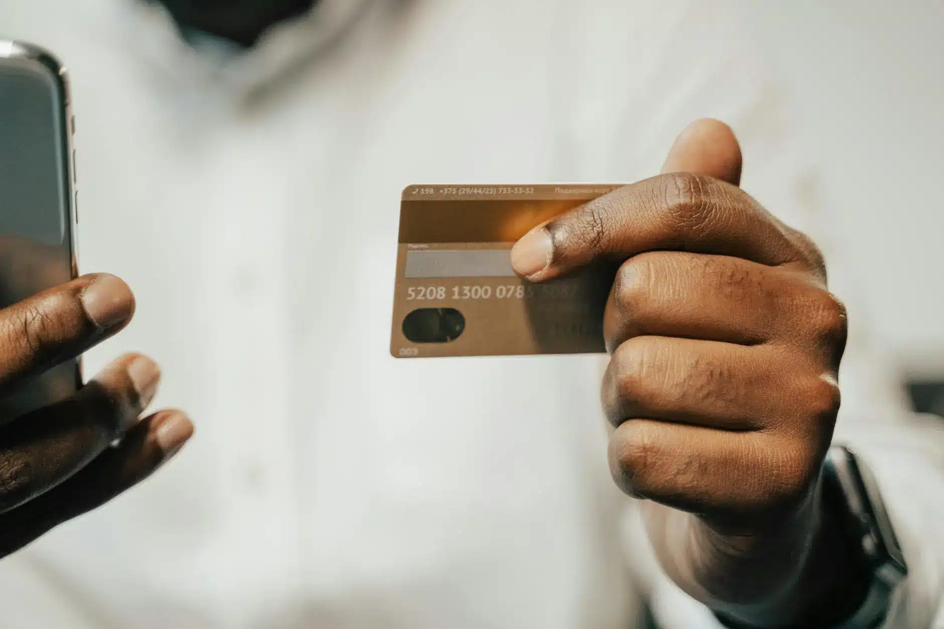 Person holding a smartphone and a payment card, illustrating mobile payment.
