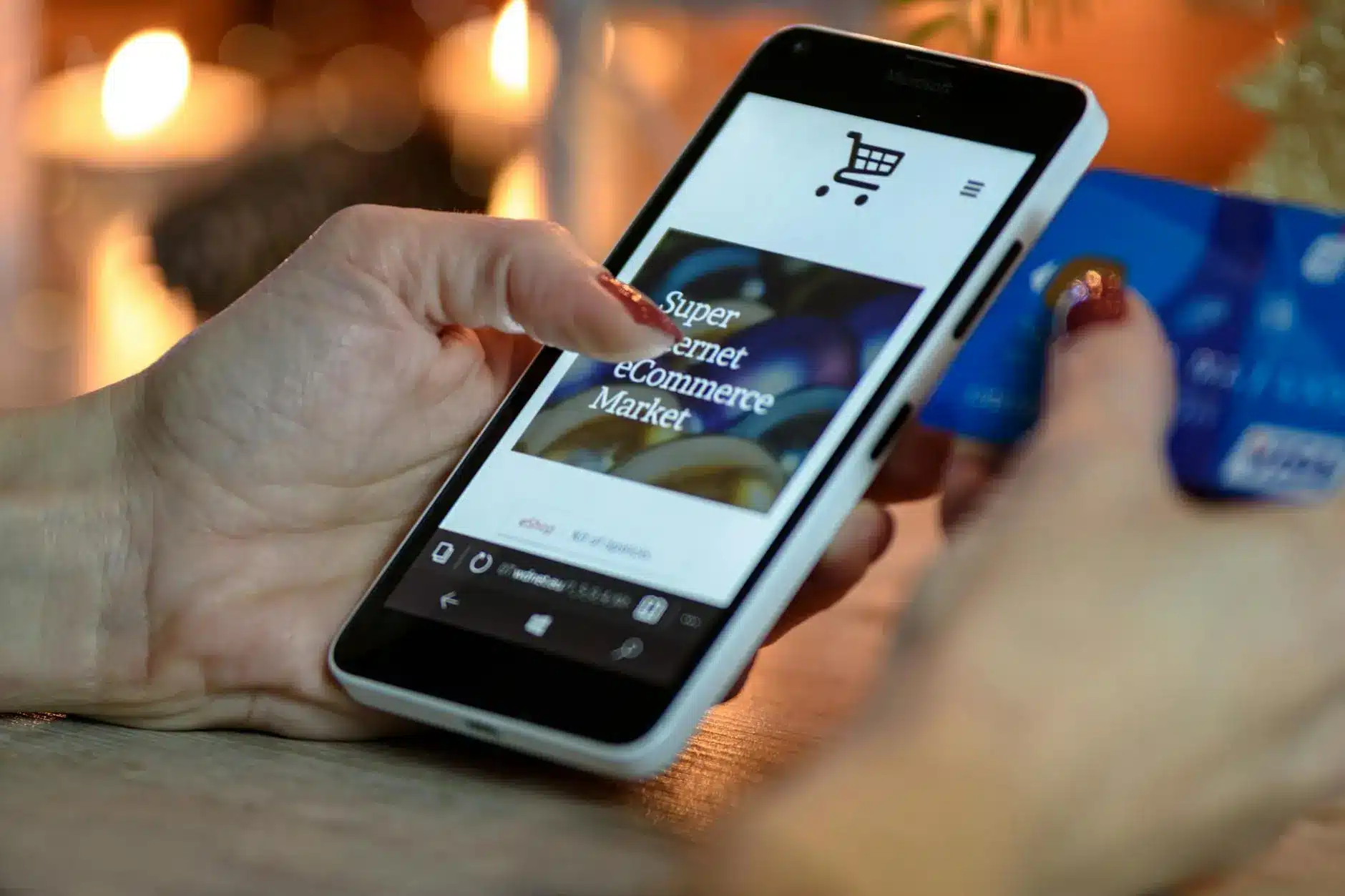 A person holding a smartphone displaying an e-commerce website with a credit card.