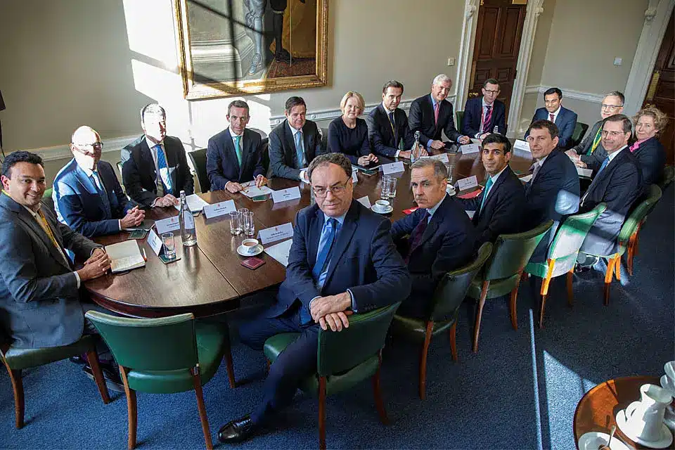 A meeting room with Bank of England officials sitting around a large table.