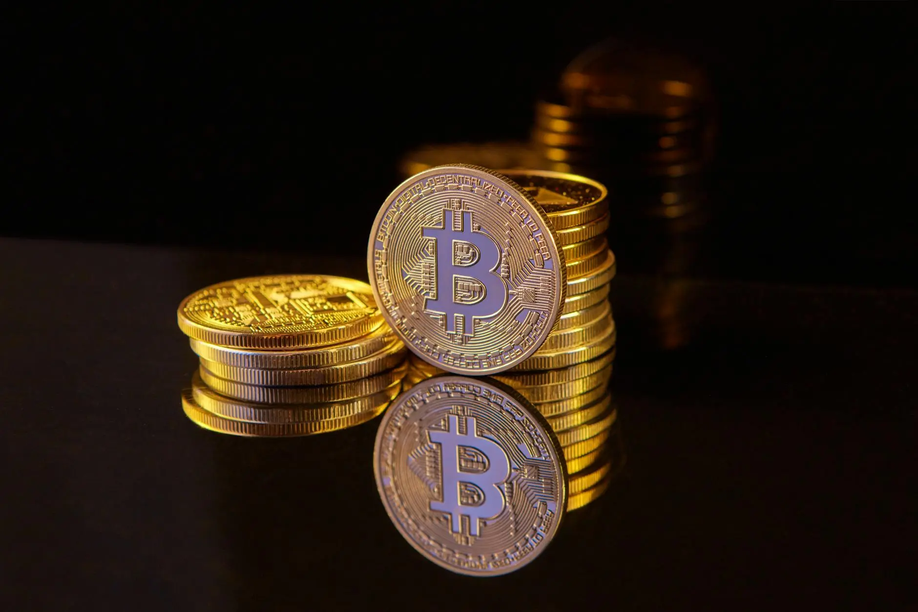 Close-up of Bitcoin coins with reflections on a dark background.
