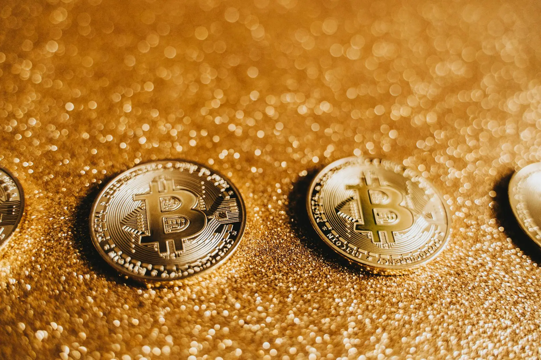 Close-up of physical Bitcoin coins on a sparkling golden surface.