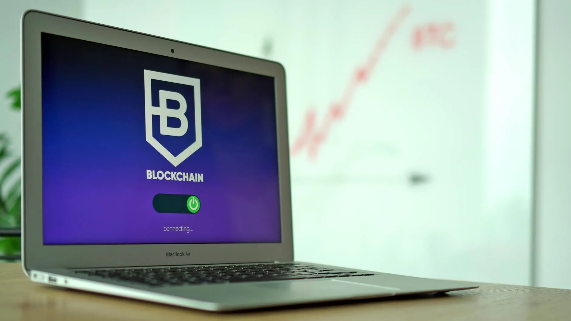 Laptop screen displaying a blockchain logo with a loading icon and connecting message.