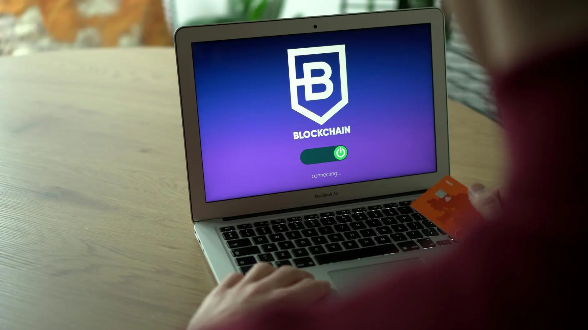 A laptop displaying a blockchain payment interface with a credit card nearby.