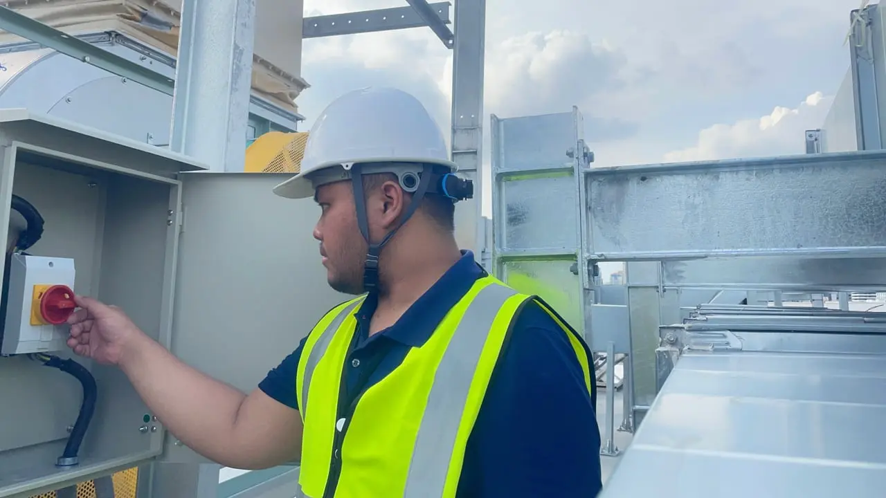 Worker in safety gear operating electrical equipment at a mining facility.