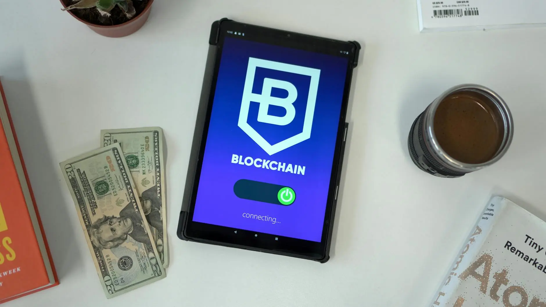 Tablet displaying Blockchain app with cash and coffee beside it.