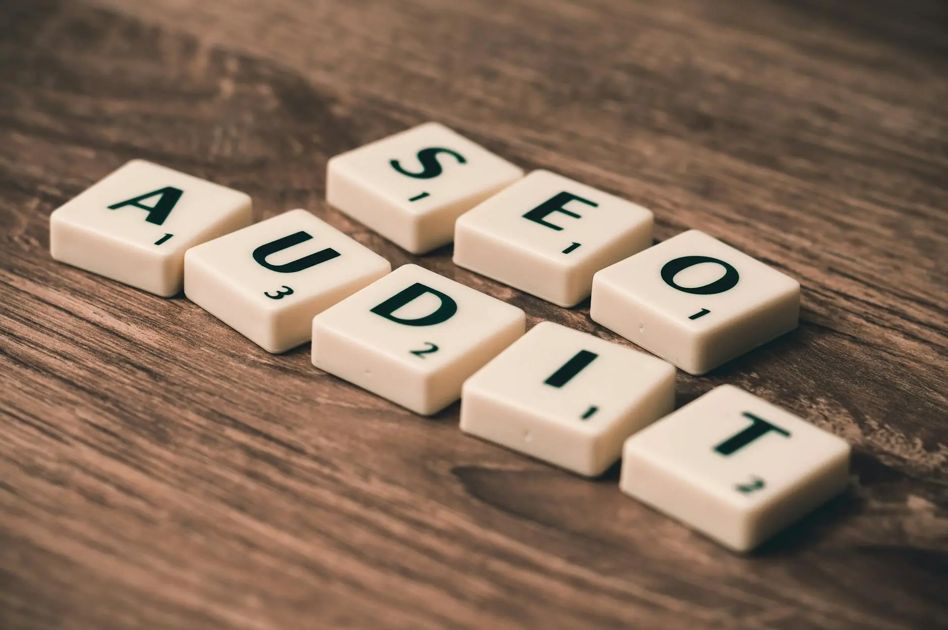 Scrabble tiles spelling 'SEO AUDIT' on a wooden surface