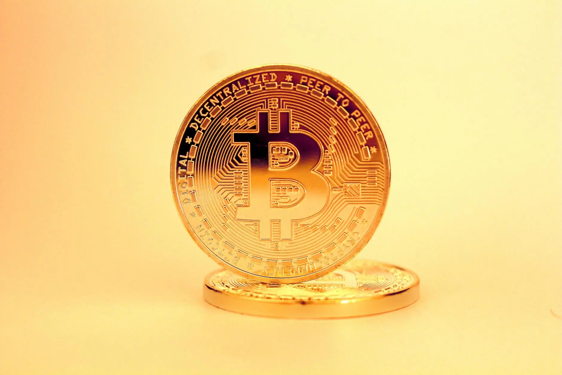 A close-up of a Bitcoin coin against a soft gradient background.