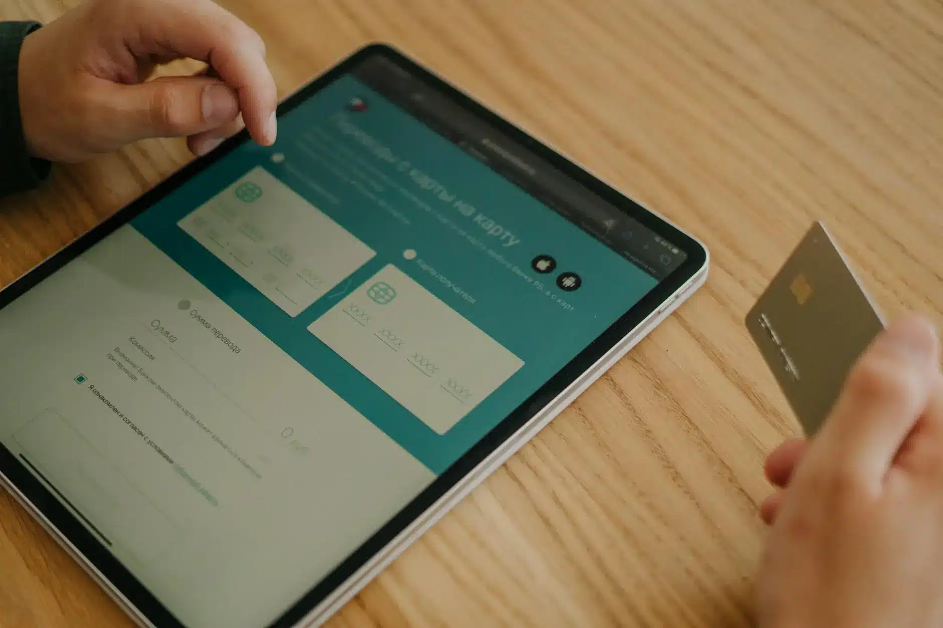 Person using a tablet with a digital payment interface and a credit card.