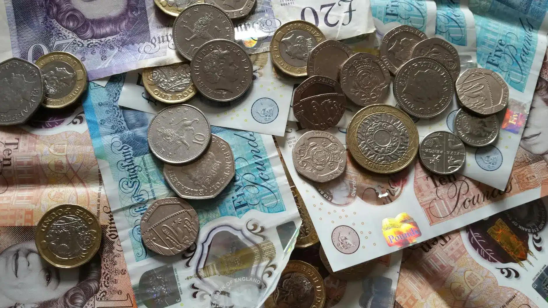 British pound banknotes and coins stacked together on a surface.