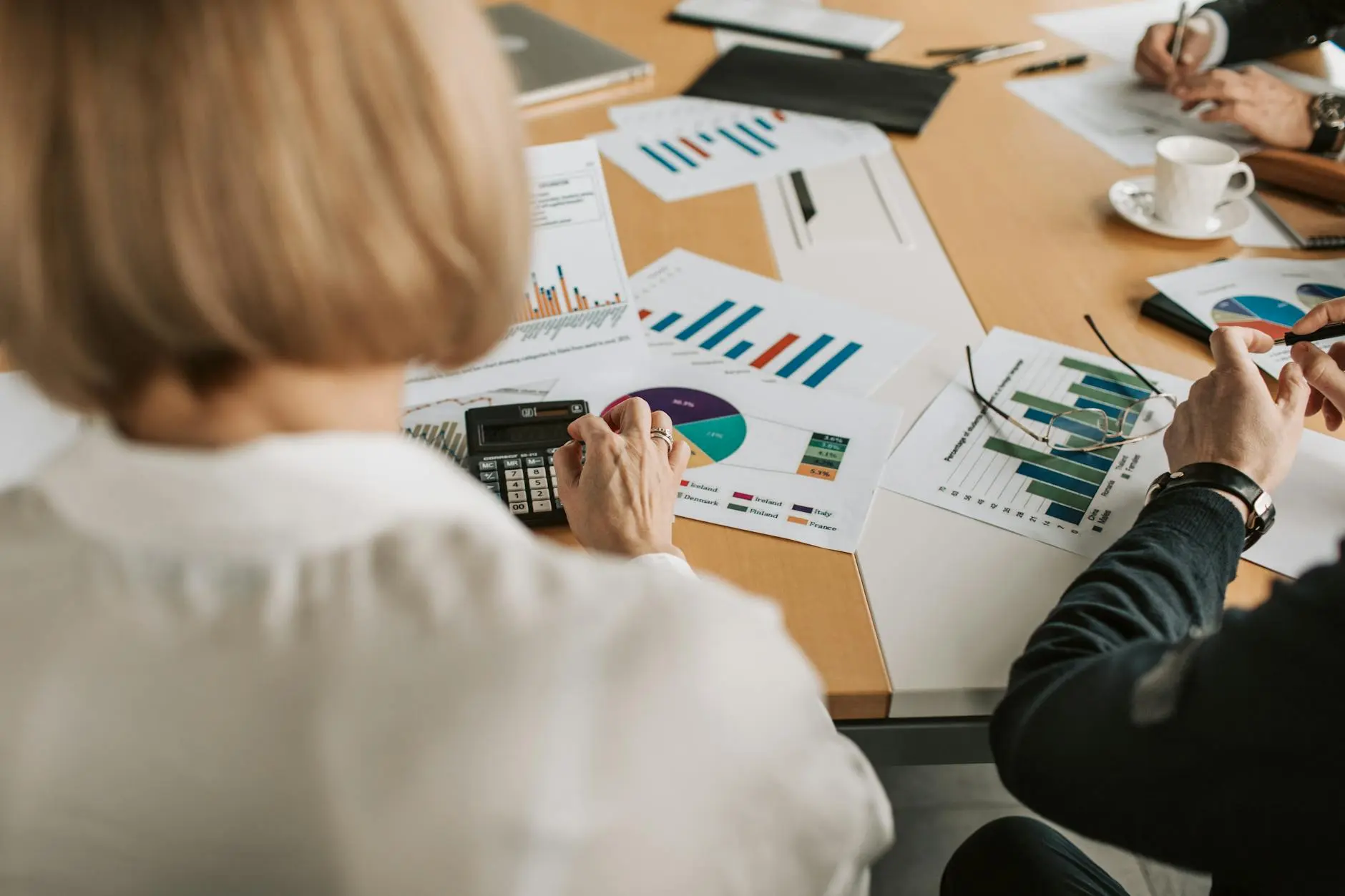A corporate meeting with financial reports and a calculator on a table.