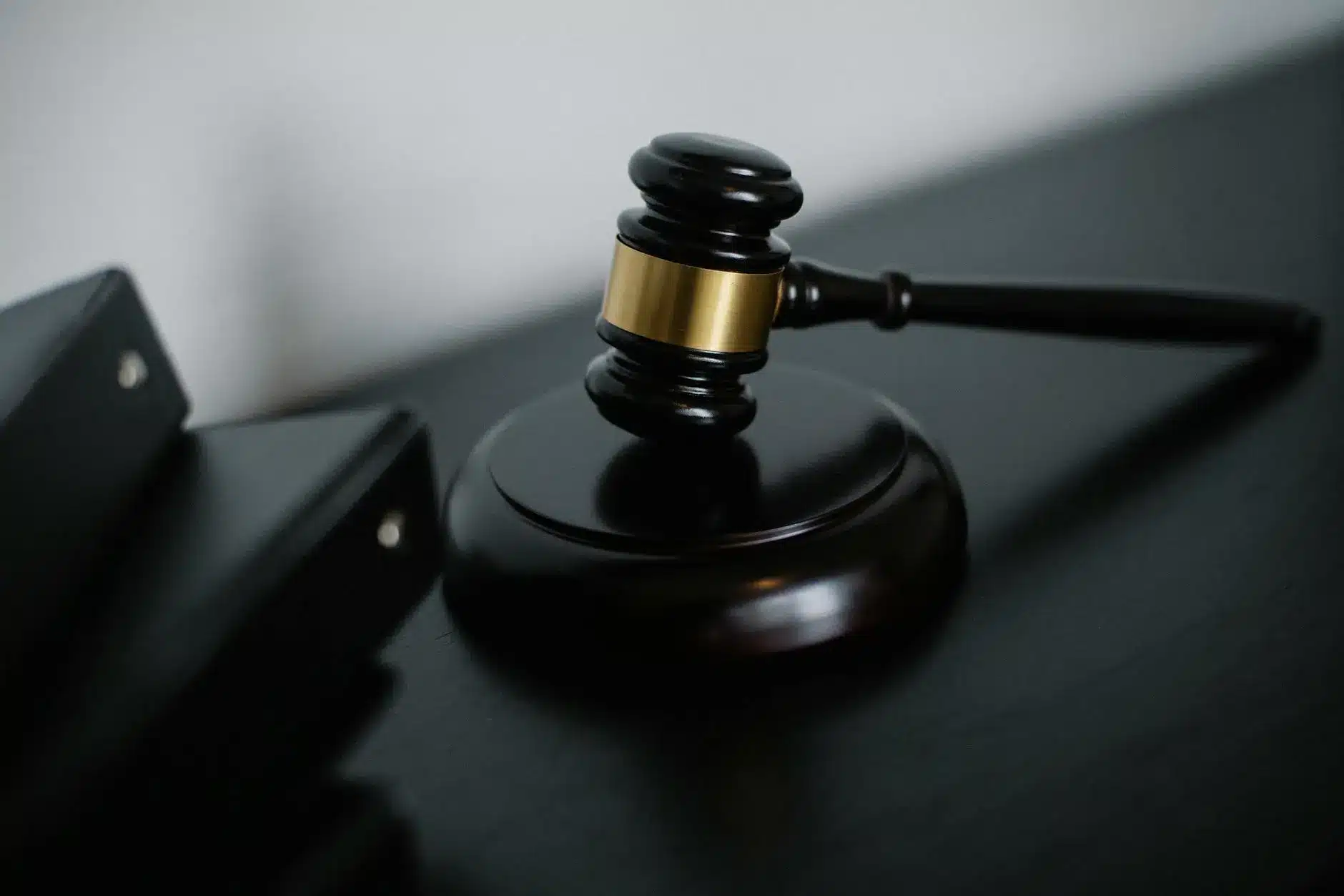 A wooden gavel with a gold band on a dark surface, symbolizing legal proceedings.
