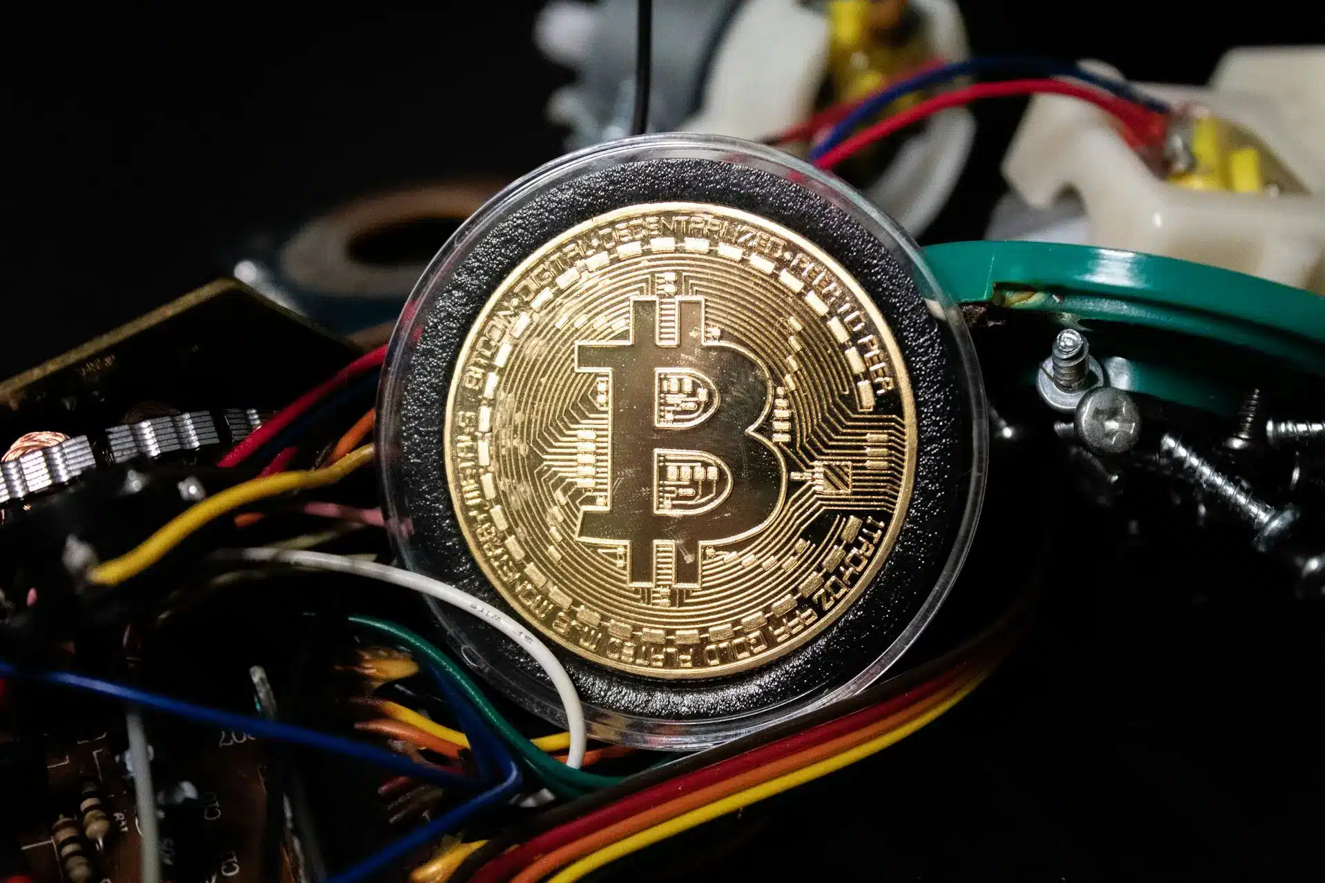 Close-up of a Bitcoin surrounded by colorful wires and circuit components.