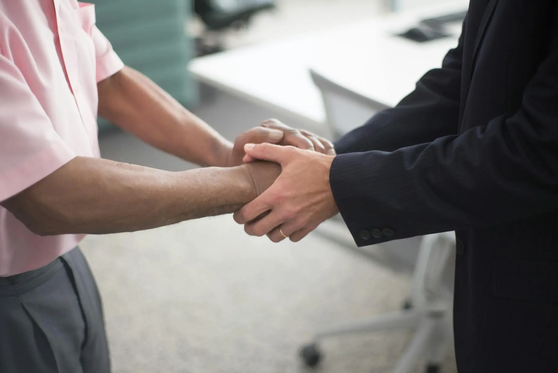 Two business professionals shaking hands in a modern office setting.