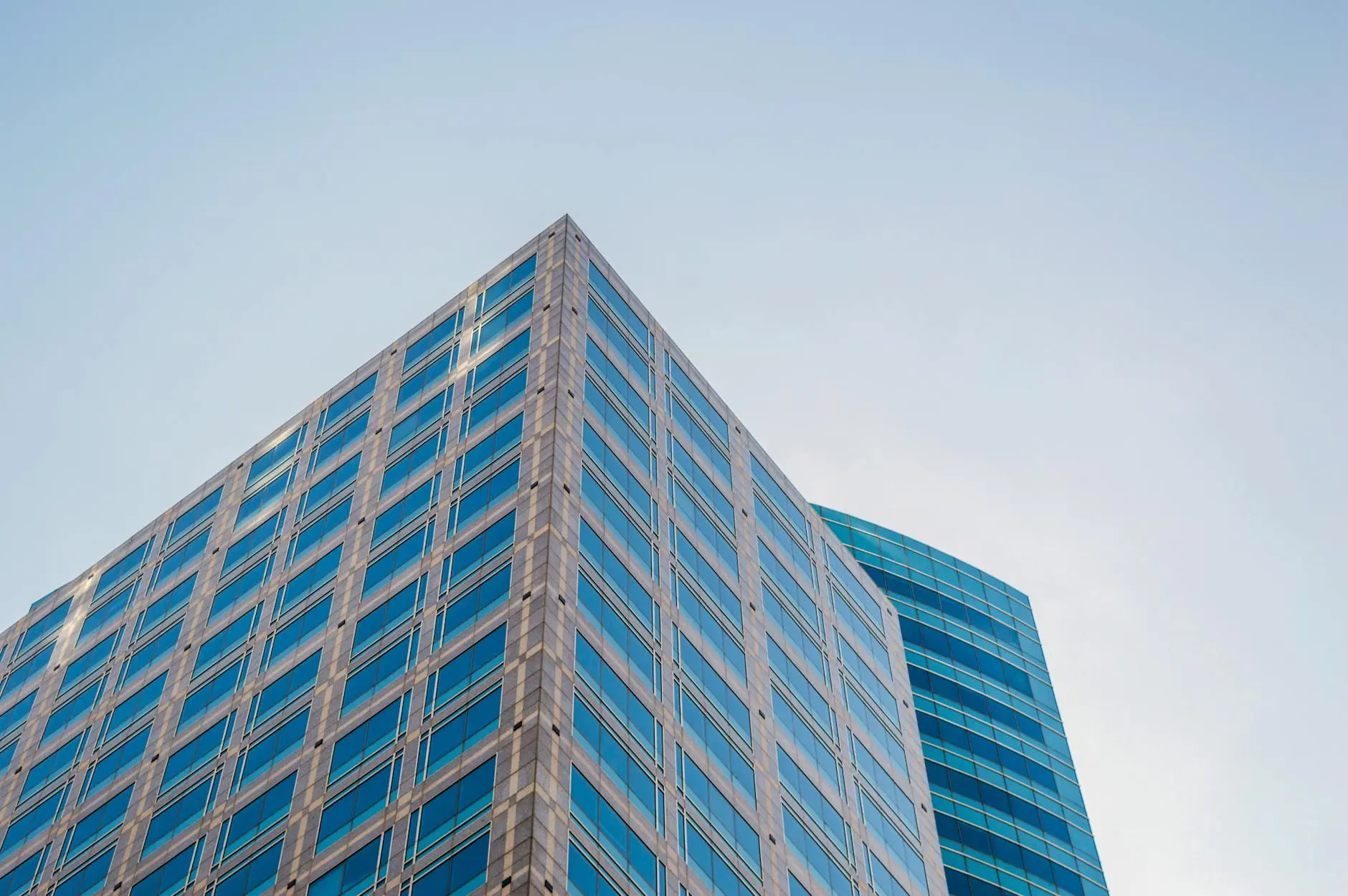 Modern corporate skyscraper with glass facade against a clear sky.
