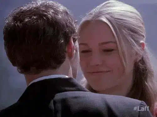 A couple sharing a tender moment, smiling at each other in a romantic setting.