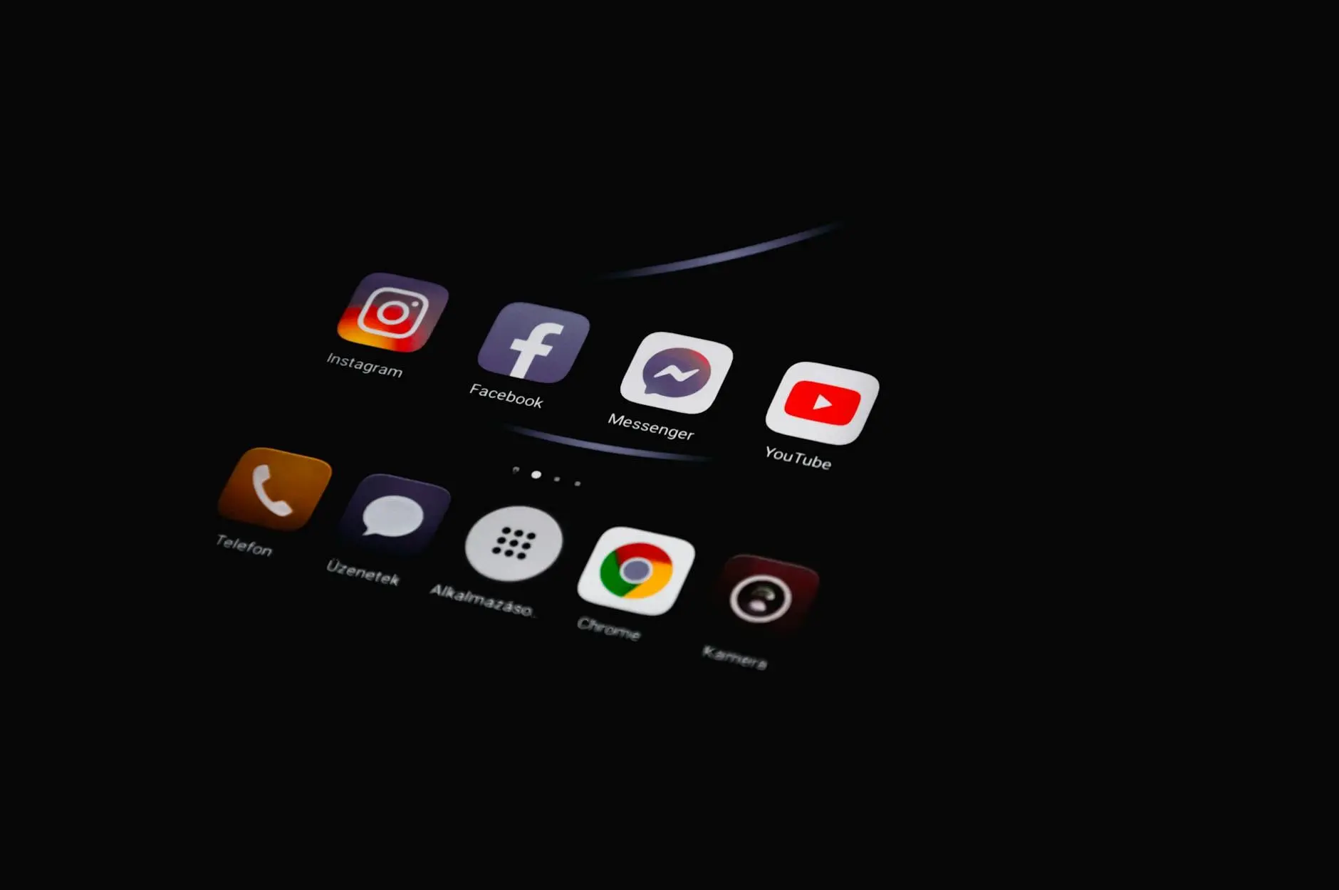 Smartphone screen displaying social media app icons in a dark setting.