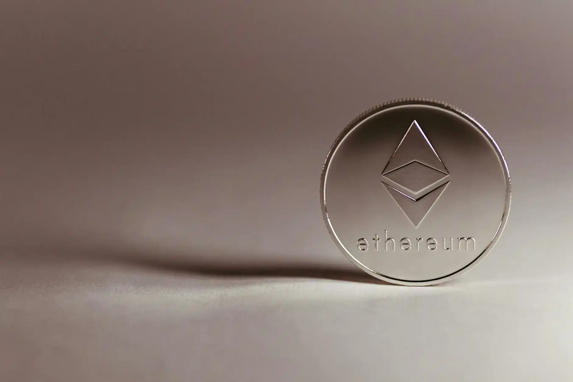 Close-up of a silver Ethereum coin on a soft surface.