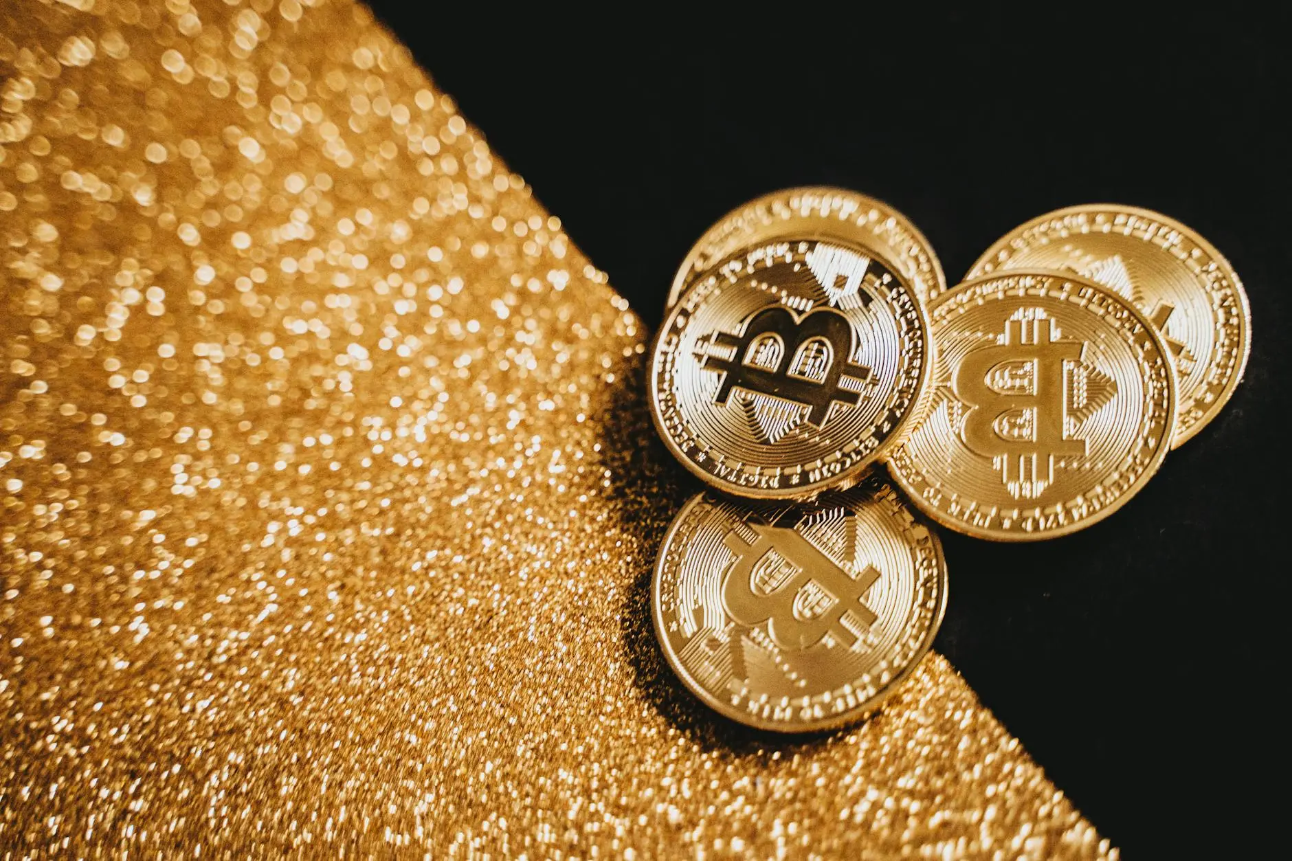 Several gold-colored cryptocurrency coins on a glittery golden surface.