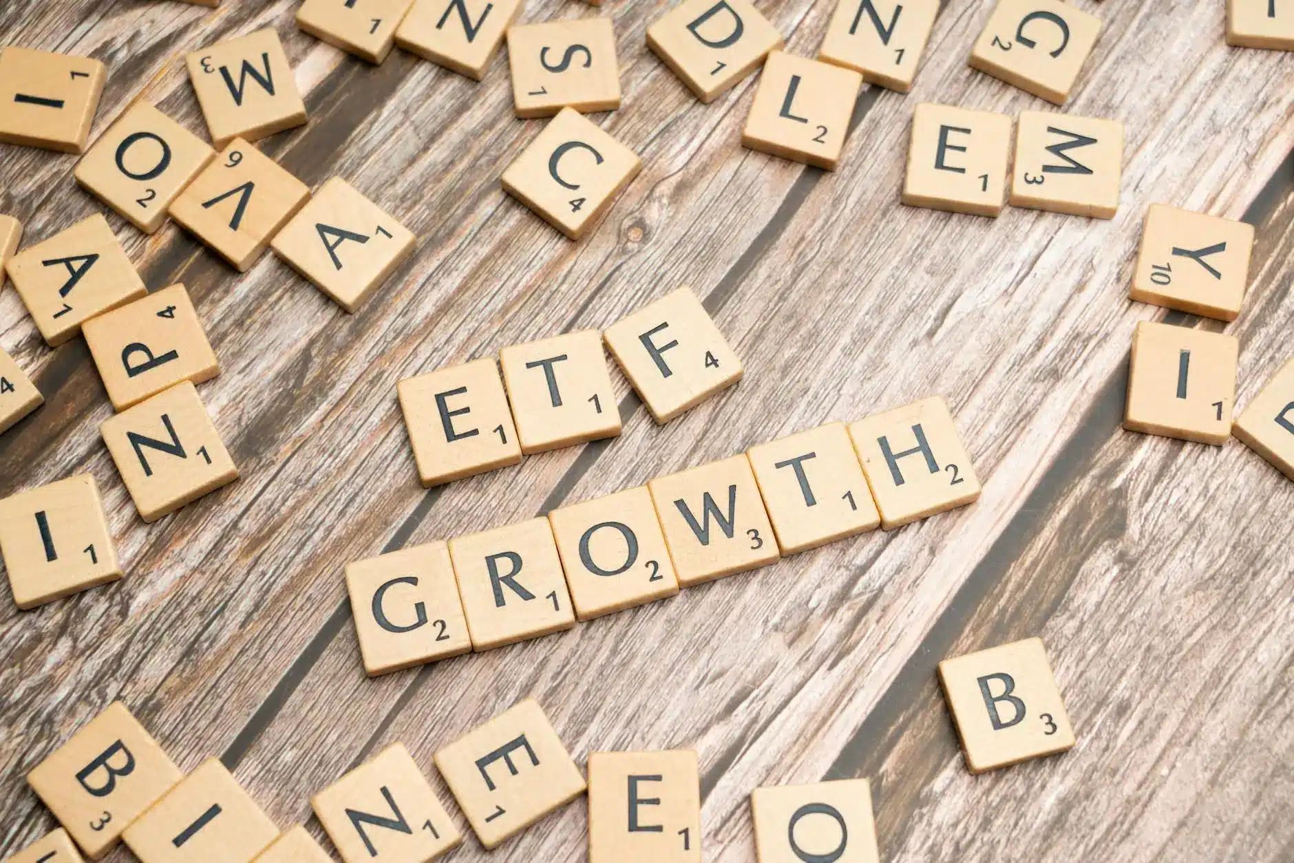 Scrabble tiles on wooden surface spell out 'GROWTH' and 'ETF'.