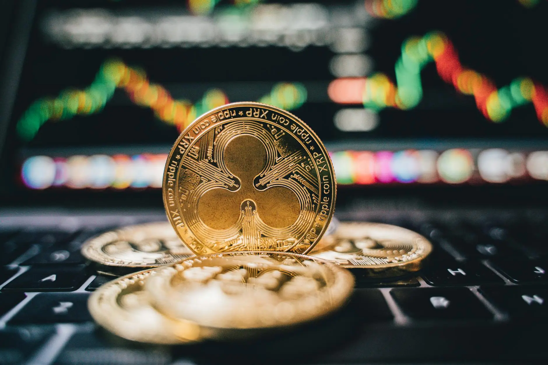 XRP cryptocurrency coins on a laptop keyboard with a price chart displayed in the background.