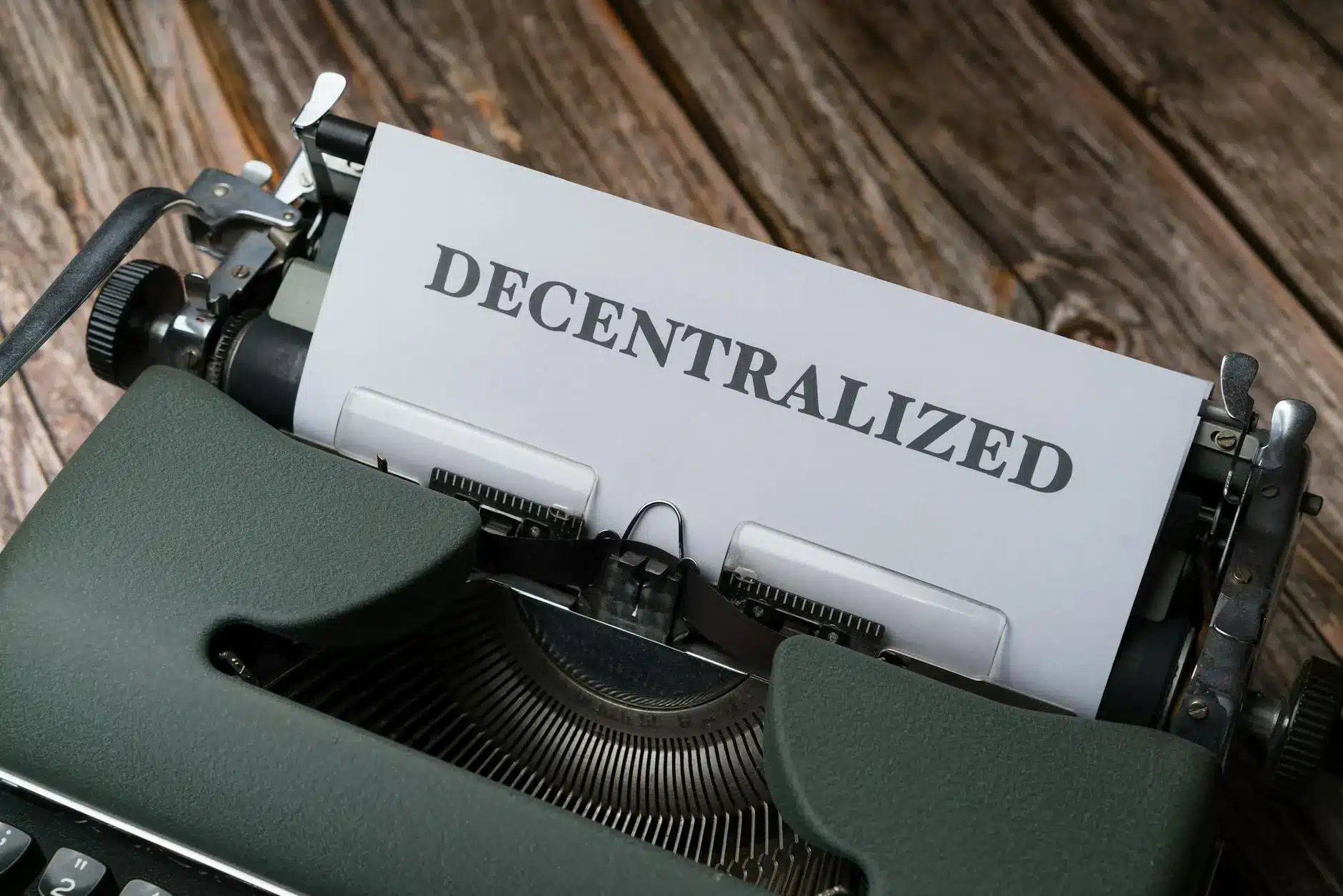An old typewriter with a sheet of paper displaying the word 'DECENTRALIZED'.