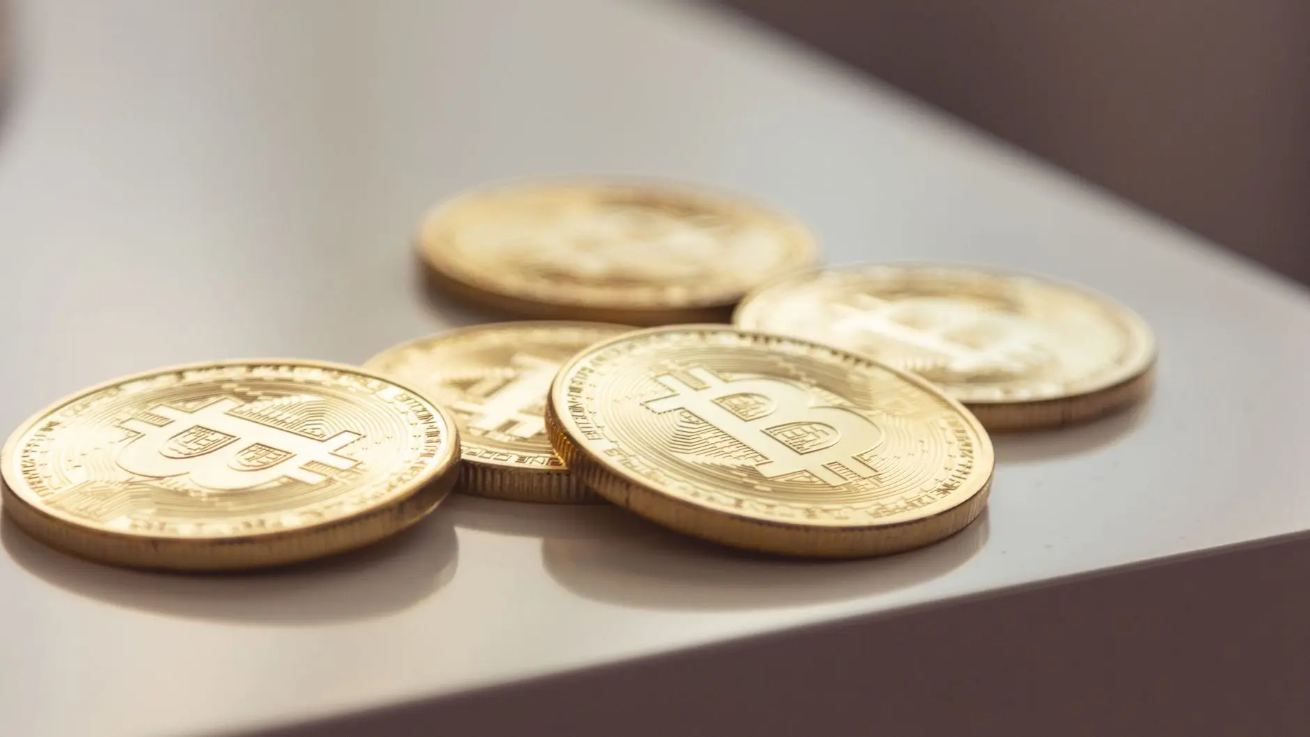 Several gold Bitcoin coins displayed on a white surface.