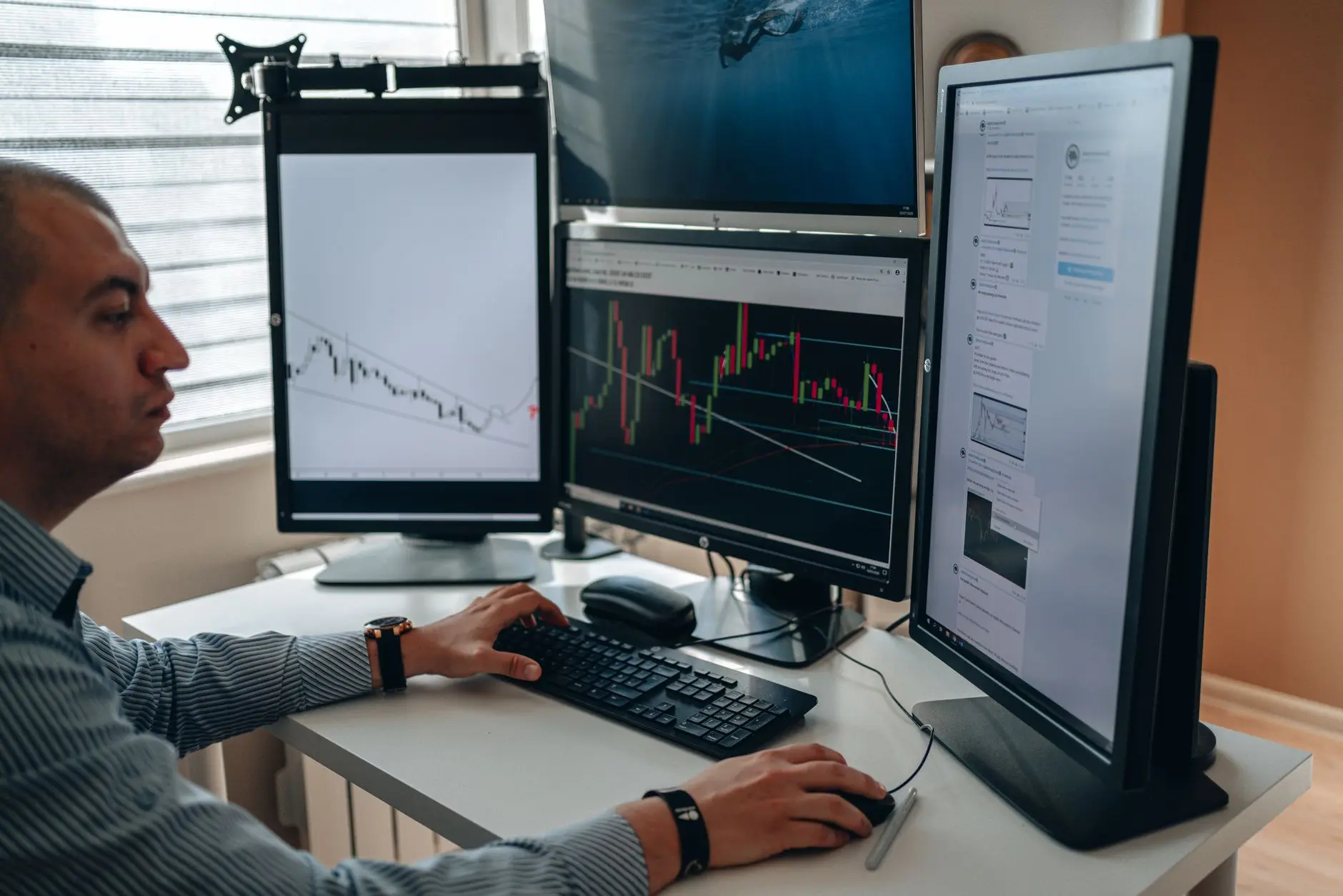 A trader analyzing financial graphs on multiple monitors at a desk.