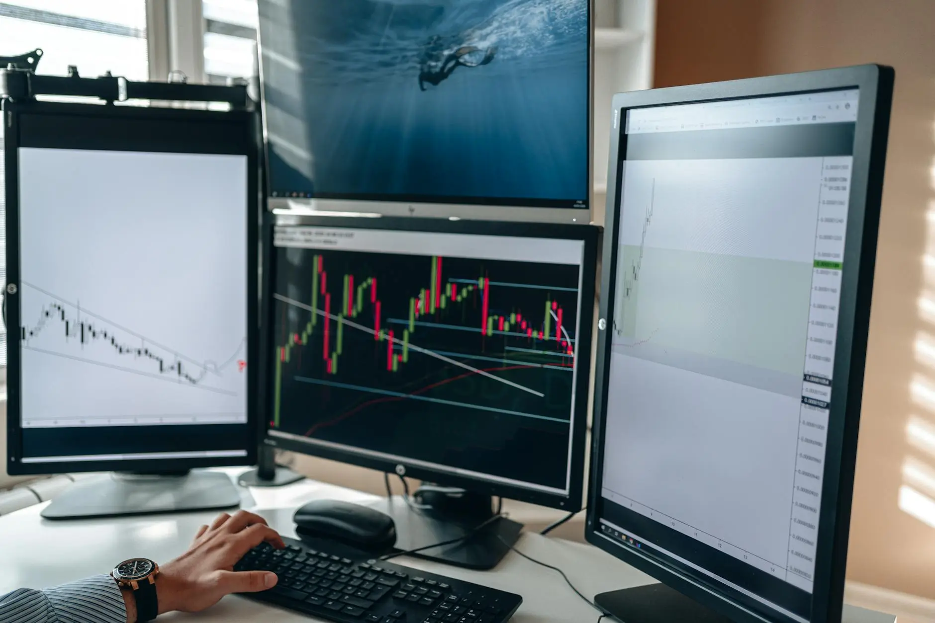 A financial trading desk with multiple monitors showing market charts and data.