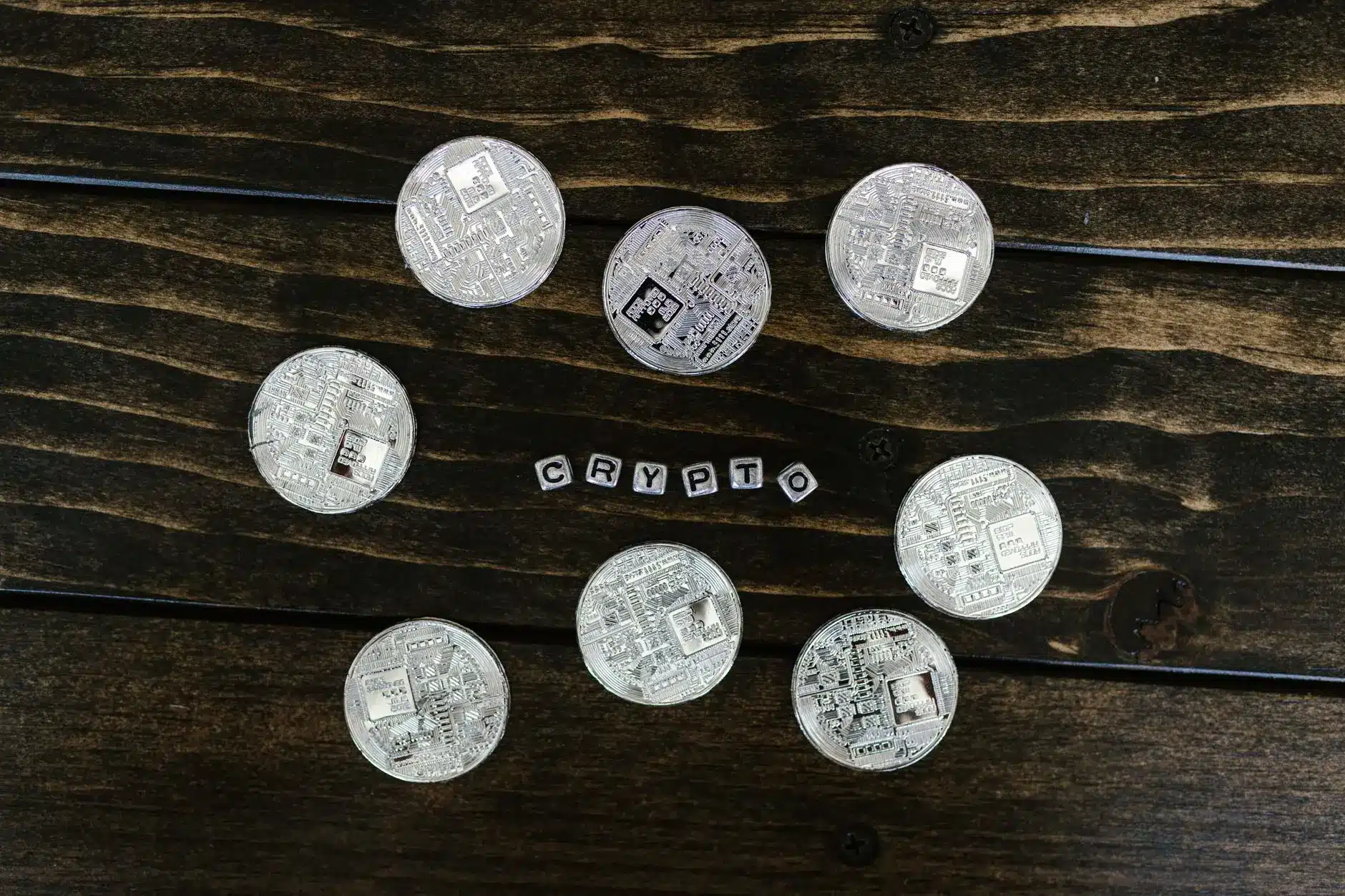 Silver crypto coins arranged with plastic letters spelling 'CRYPTO'.