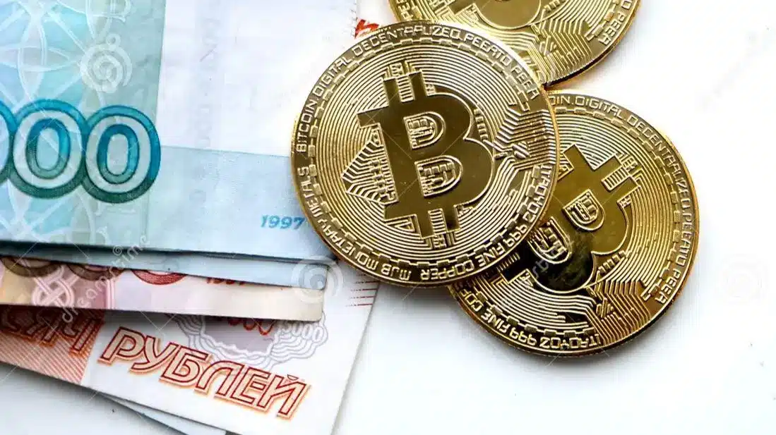 Three Bitcoin coins on Russian ruble banknotes.